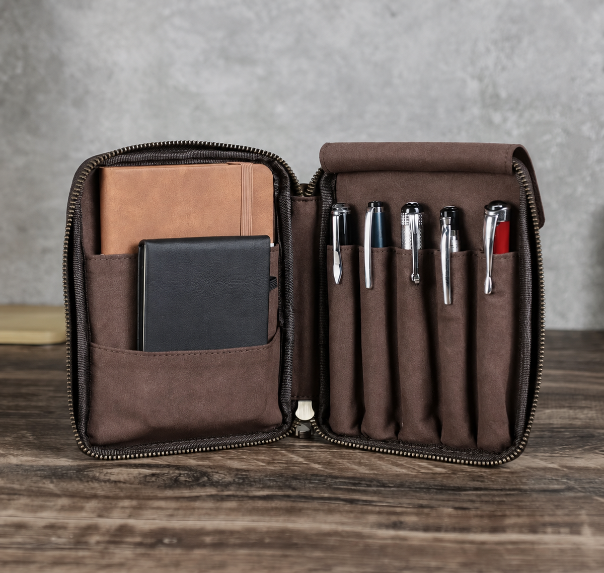 Leather pen case holding five pens with an A6 notebook and phone pocket